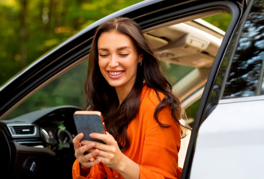 Mujer en un auto con un celular en la mano